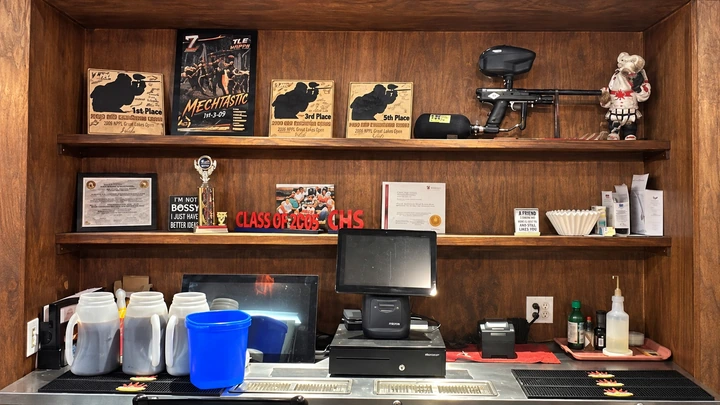 The restaurant’s wooden display shelves with a paintball gun, awards, and local keepsakes.